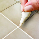 Mao aplicando a caneta de rejunte na linha entre azulejos bege