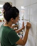 Mulher renovando com a caneta Rinova o rejunte escurecido da parede da cozinha